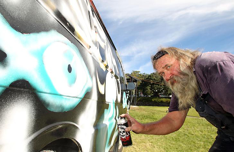 9) Уличный художник расписывает старый автомобиль из баллончика.