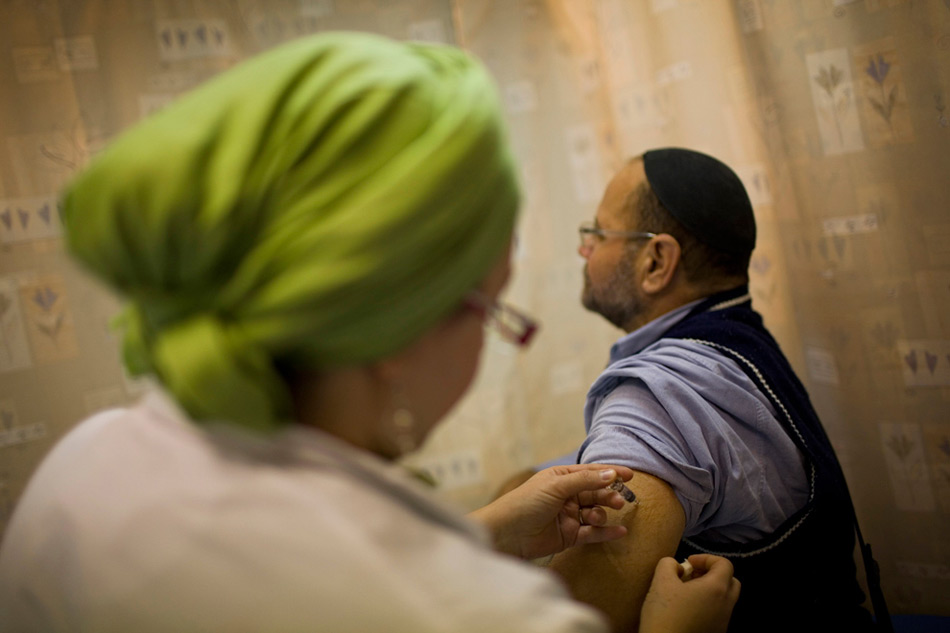 18. Израильская медсестра делает мужчине инъекцию против вируса H1N1 в иерусалимской клинике в среду 4 ноября 2009 года. (AP Photo/Bernat Armangue)