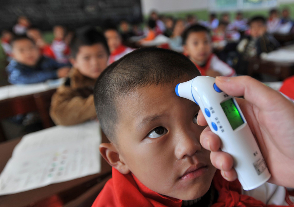 24. Учитель меряет температуру школьника в целях профилактики свиного гриппа в начальной школе в Ухане, провинция Хубэй, в понедельник 2 ноября 2009 года. (AP Photo)