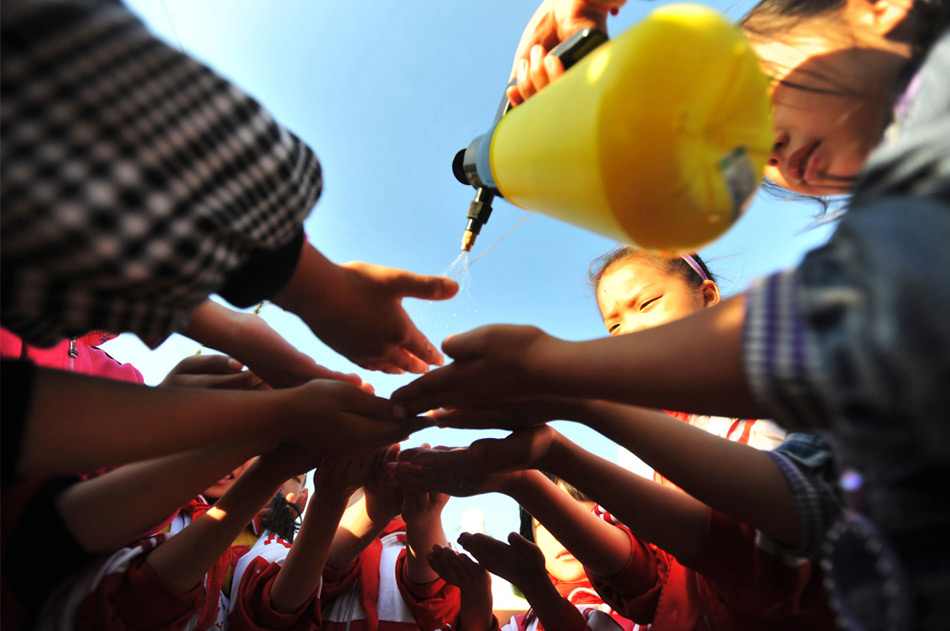 27. Учитель брызгает спиртом на руки школьникам во время профилактики распространения вируса гриппа H1N1 в начальной школе в Ухане, провинция, Хубэй, Китай, 2 ноября 2009 года. (AP Photo)