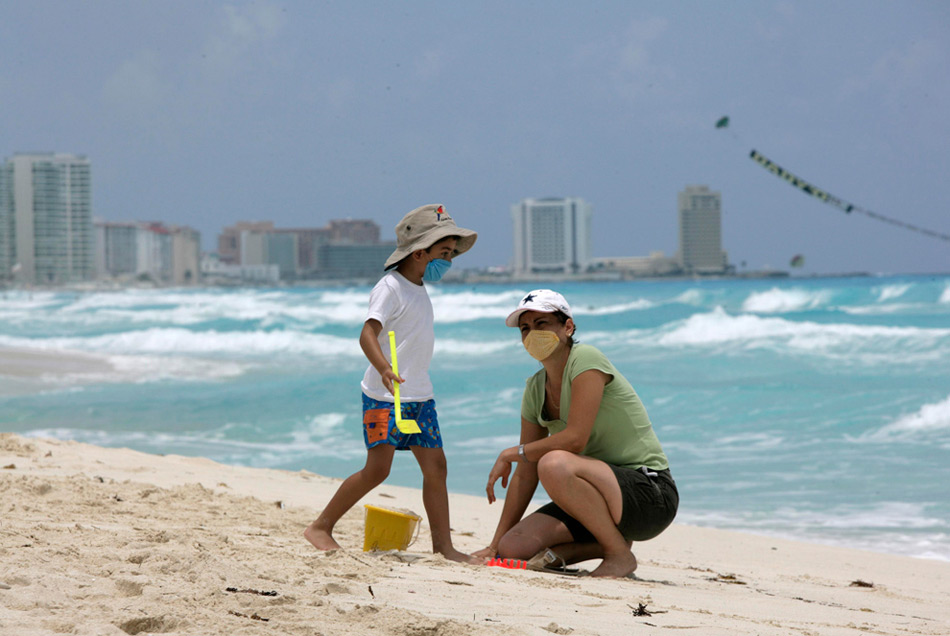 30. Кевин Солис и его мать Абди Сантойо в масках против вируса свиного гриппа на пляже в Канкуне, Мексика. (AP Photo/Israel Leal )