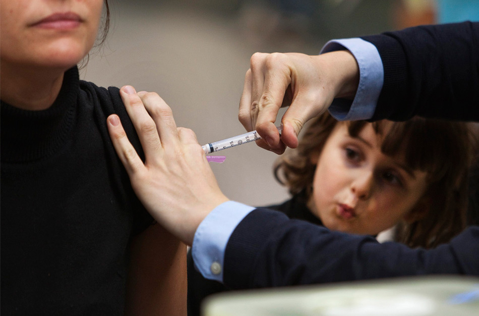37. Девочка смотрит, как ее матери делают прививку против вируса гриппа H1N1 в Ванкувере 26 октября 2009 года. (REUTERS/Andy Clark)
