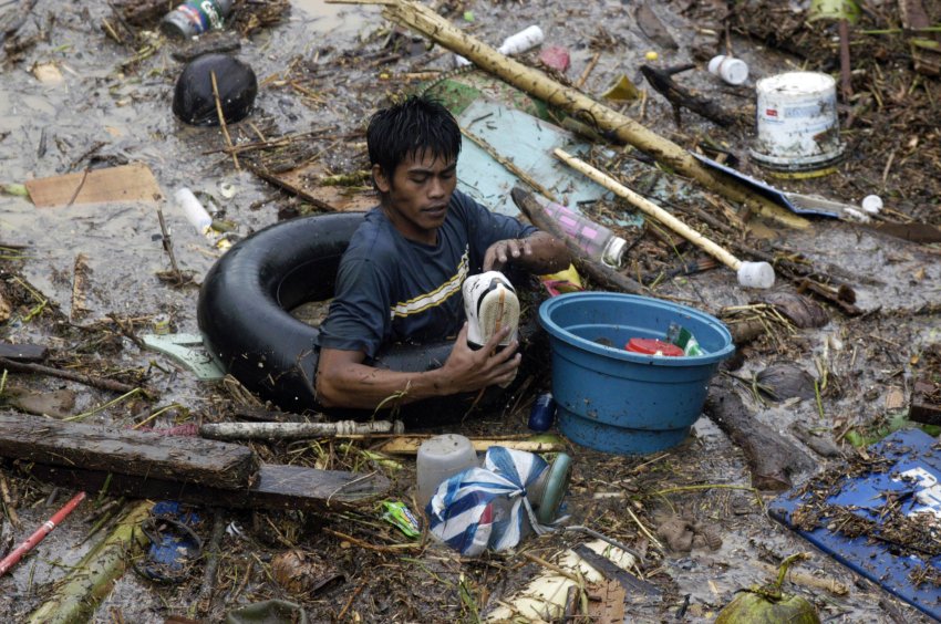 Житель города Кагаян-де-Оро прокладывает себе путь через воду и отходы