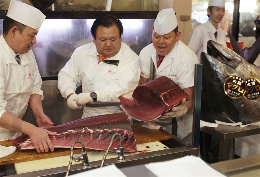 Киеси Кимура (в центре слева) разрезает голубого тунца в его ресторане Суши Zanmai