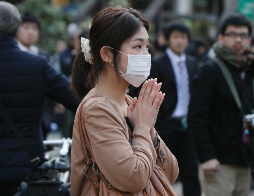 Молодая женщина во время минуты молчания в Токио