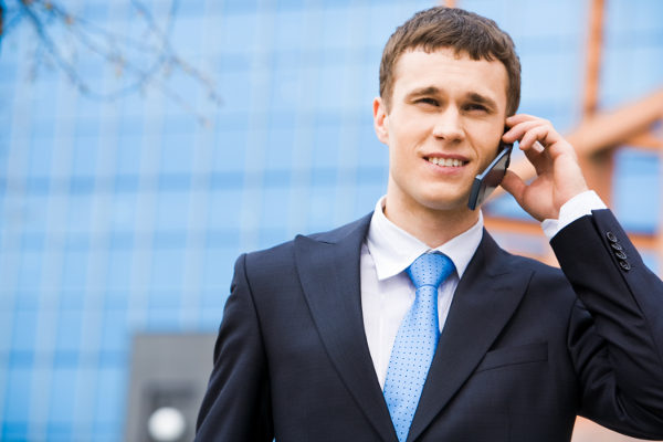 Portrait of successful young man calling on cellular phone outside